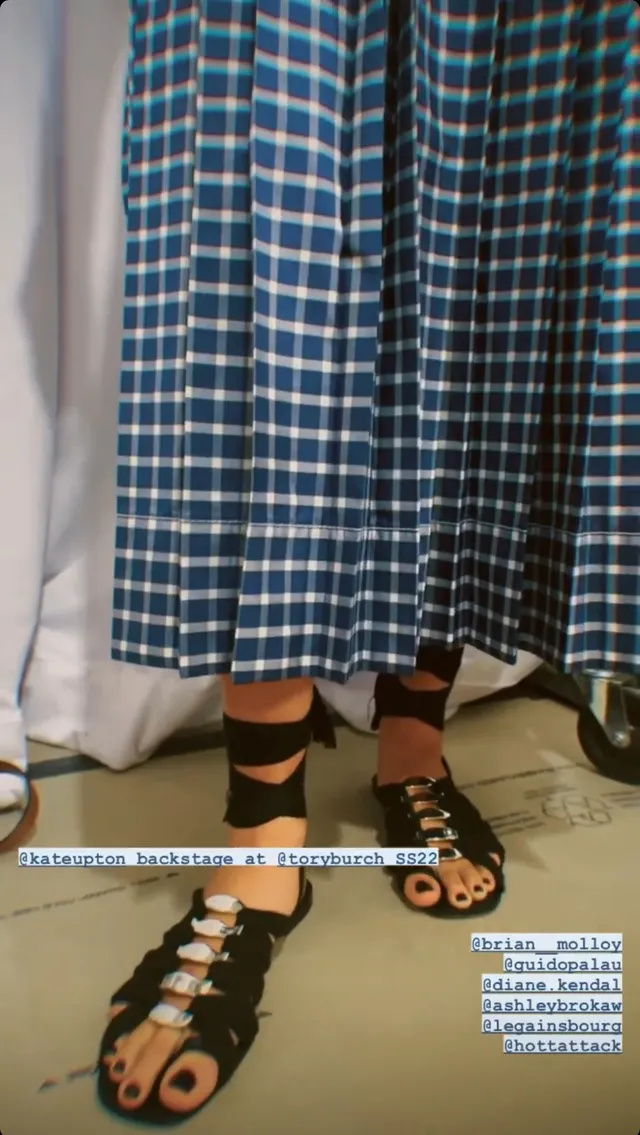 Kate Upton wearing black sandals beneath a checked hem.