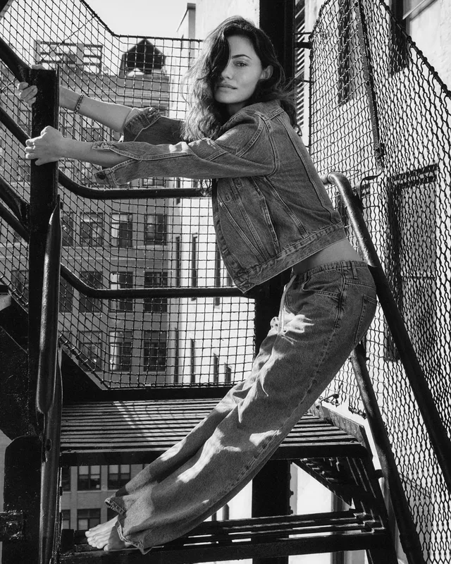 Phoebe Tonkin posing on a fire escape in jeans.