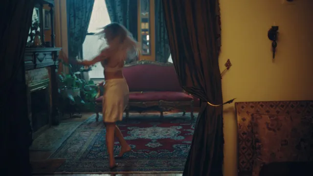 Grace VanderWaal standing barefoot beside a staircase.
