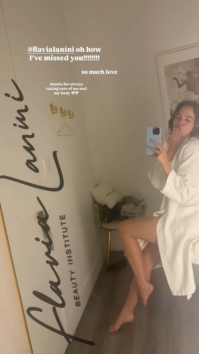 Bailee Madison taking a mirror photograph barefoot in a white robe.