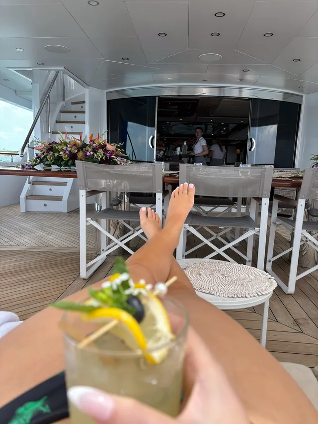 Iggy Azalea resting crossed bare feet on a boat while holding a drink.