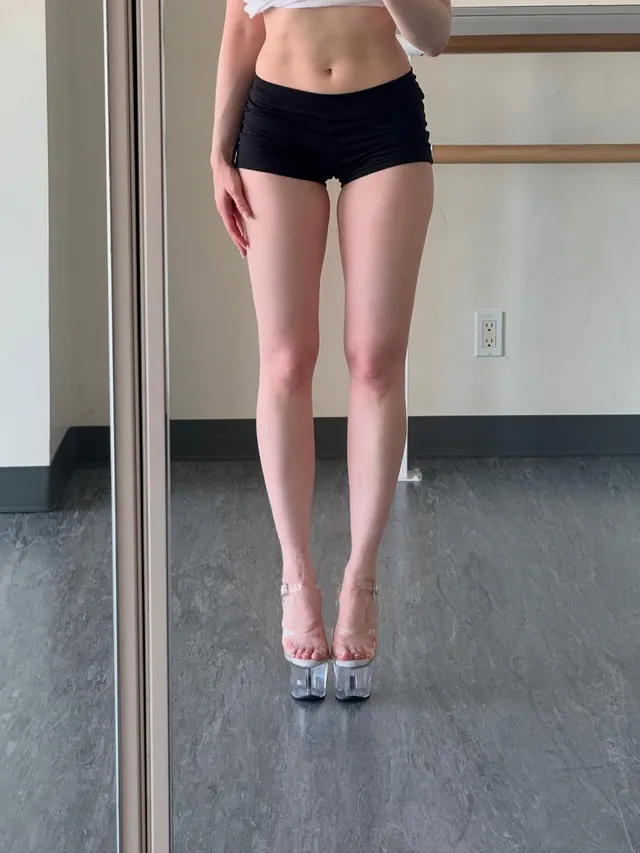 Madelaine Petsch wearing pale high heels beneath black shorts.