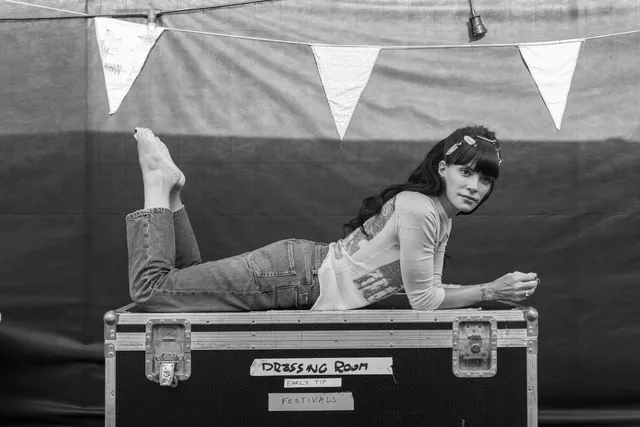 Lily Allen lying on a backstage equipment case.