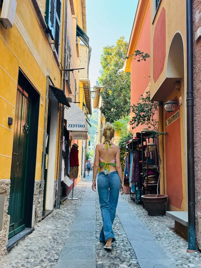 Christina Aguilera walking along a narrow street in jeans and heels.