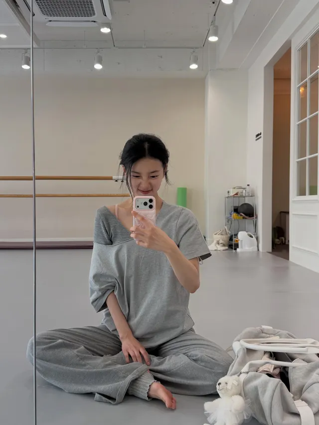 Bae Suzy sitting barefoot on a dance studio floor.