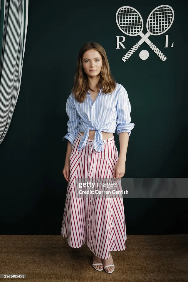 Freya Allan wearing a striped shirt, long skirt and pale heels at an event.