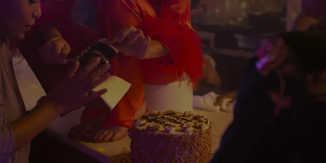 Odessa A'zion sitting beside a birthday cake in a scene.