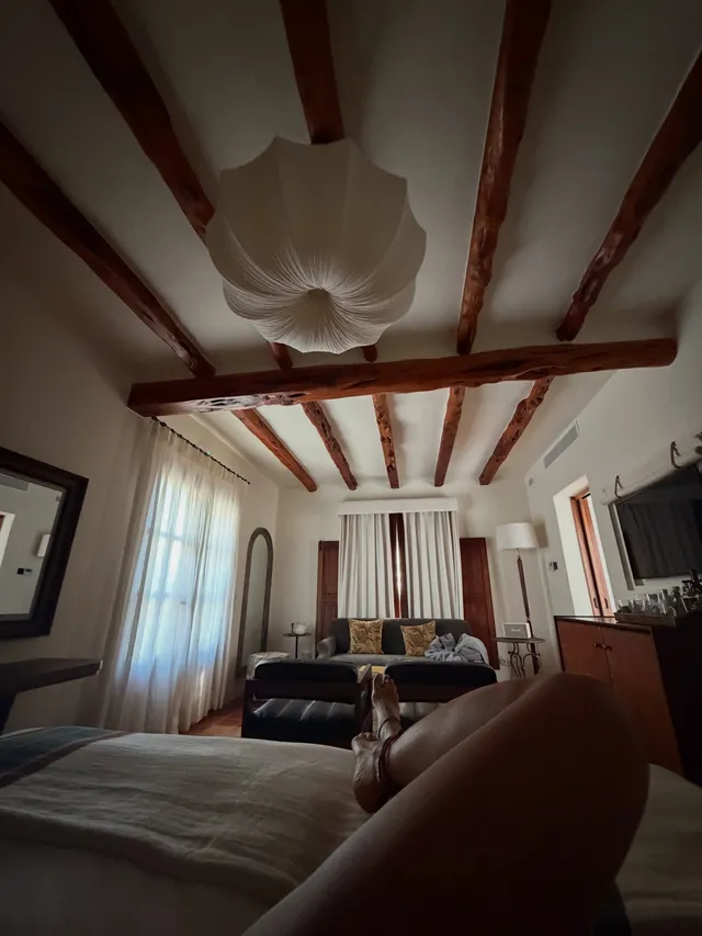 Rita Ora relaxing in a room with exposed ceiling beams.
