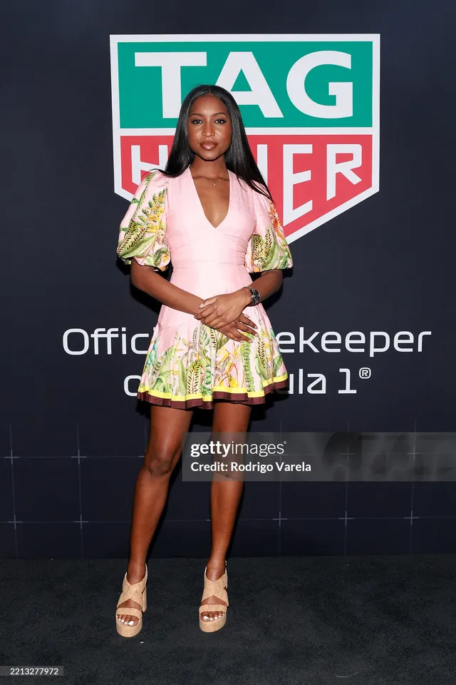 Carlacia Grant posing in a pink patterned outfit and pale heels at an event.