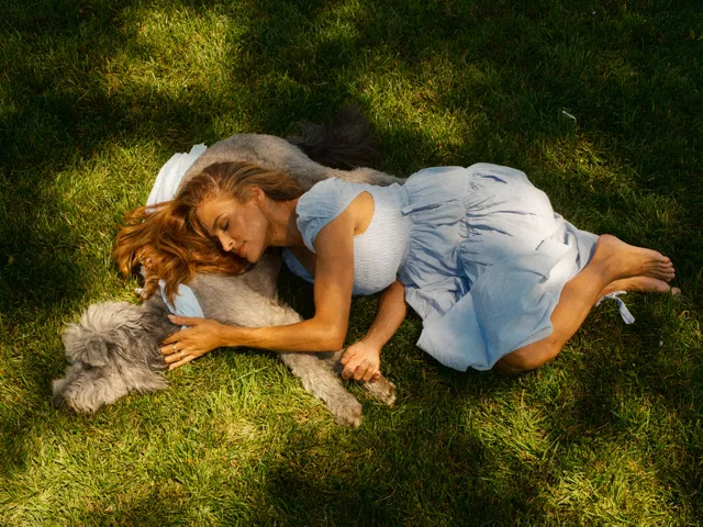 Eva Mendes lying on grass beside a dog.