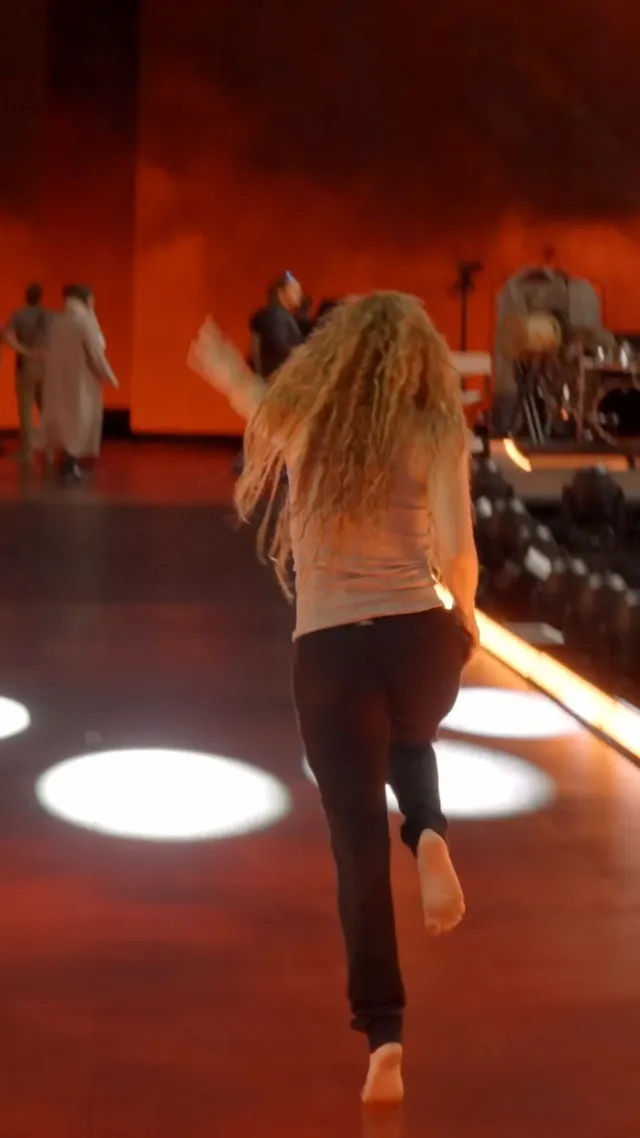 Shakira dancing barefoot during rehearsals with one sole raised.