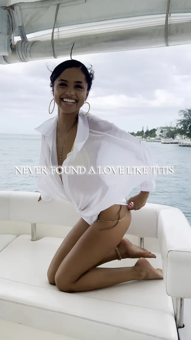 Tyla kneeling barefoot on a boat seat in a white shirt.