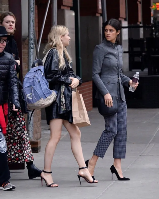 Freya Allan walking beside another woman in a black outfit and heels.