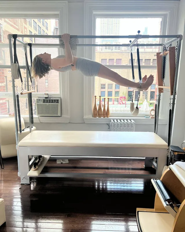Chloë Grace Moretz stretching barefoot on an exercise machine.