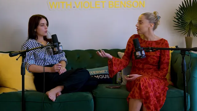 Adelaide Kane sitting cross-legged during a podcast interview.