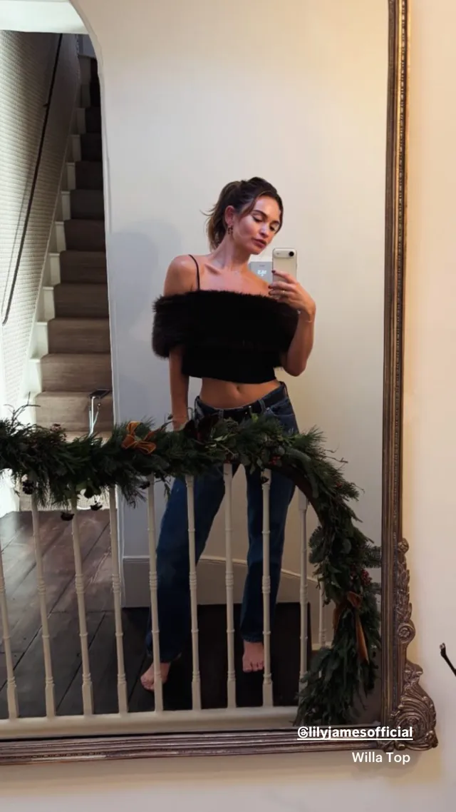 Lily James posing barefoot beside a stair railing.