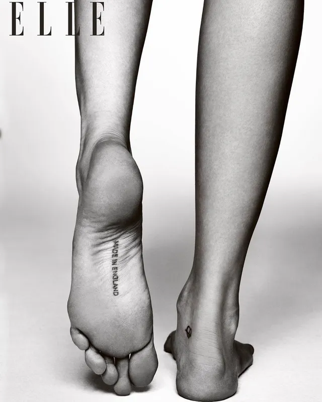 Cara Delevingne showing a foot tattoo in a monochrome fashion photograph.