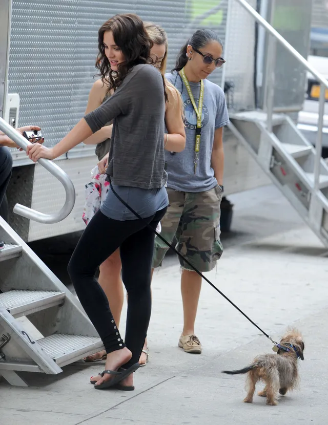 Leighton Meester walking a dog in leggings and flip-flops.