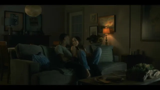 Victoria Pedretti reclining on a sofa with a companion during a screen scene.