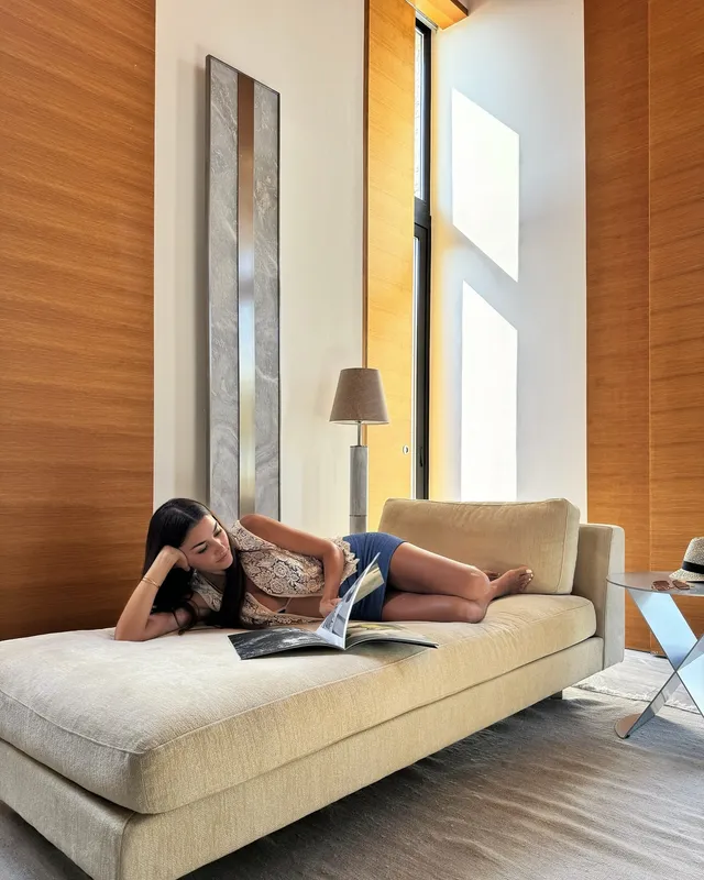 Hande Erçel reclining barefoot on a sofa.