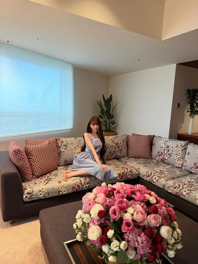 Jang Wonyoung sitting barefoot on a patterned sofa.