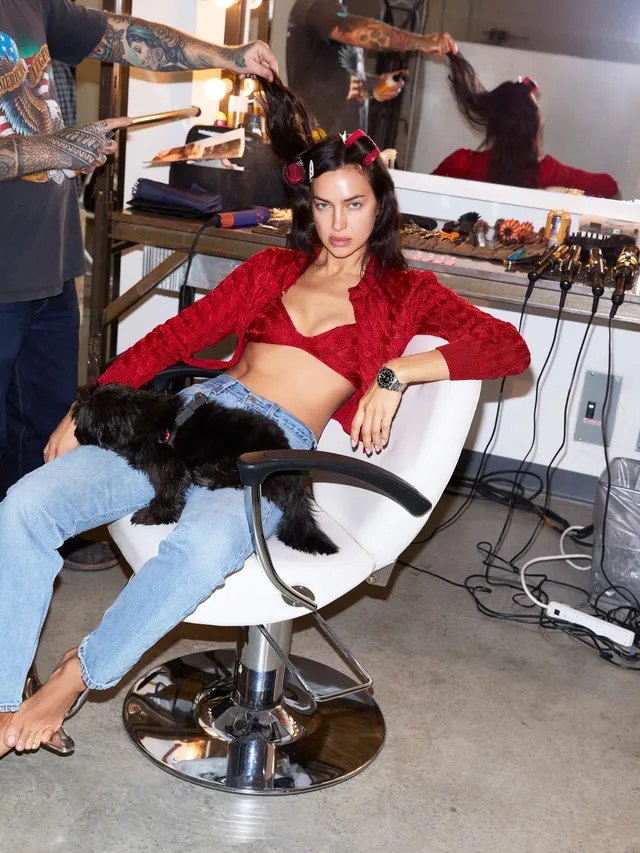 Irina Shayk a red top and jeans in a styling chair.
