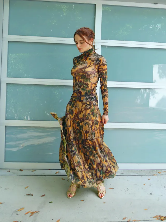 Joey King wearing a long floral dress and metallic heels outdoors.
