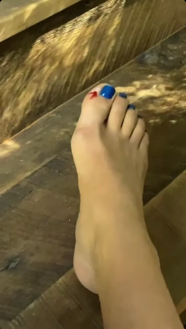Florence Pugh a close detail of a bare foot with painted toenails.