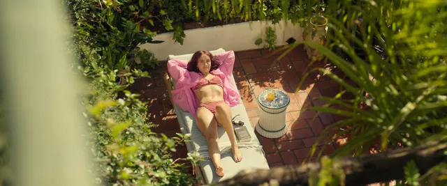Olivia Cooke reclining in an outdoor chair in a screen scene.