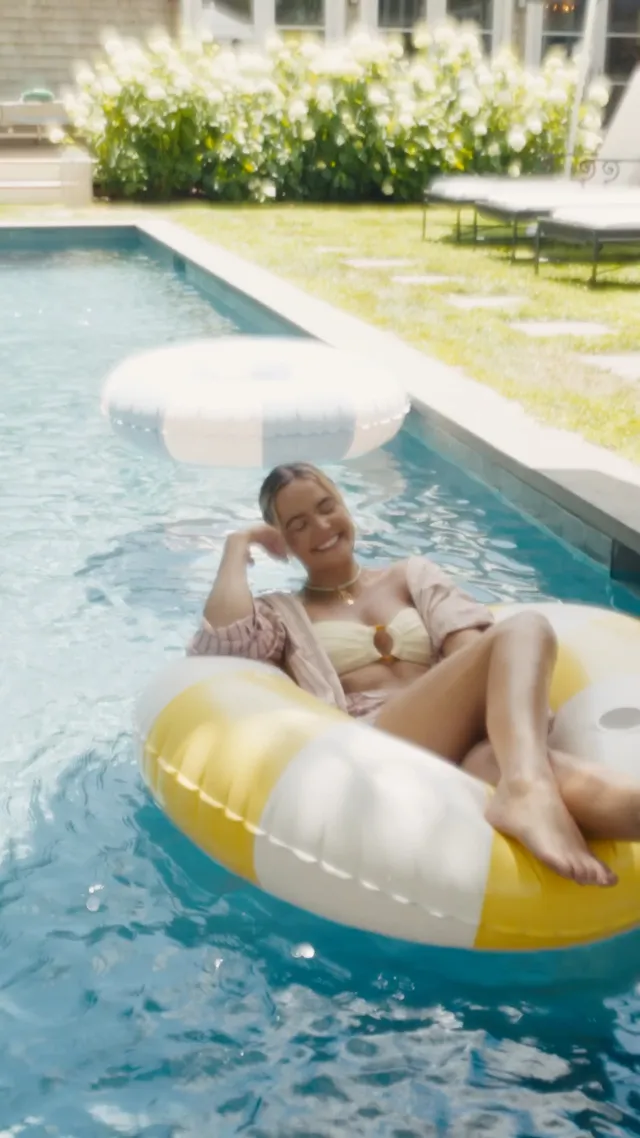 Bailee Madison floating barefoot in a swimming pool.