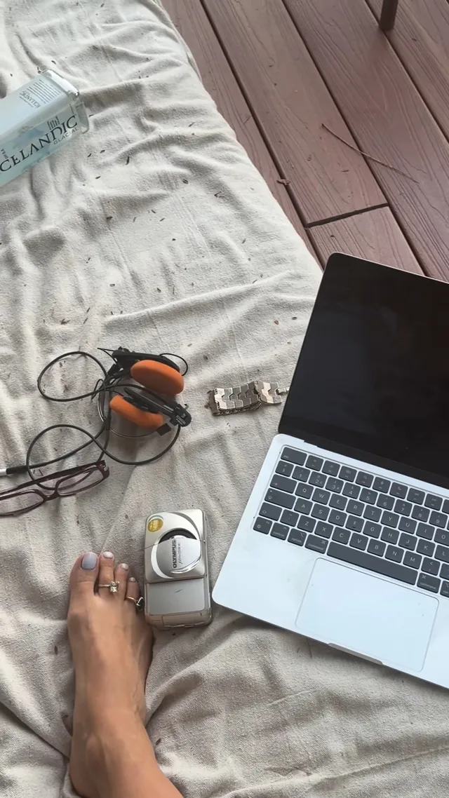 Rita Ora resting a bare foot beside a laptop and headphones.