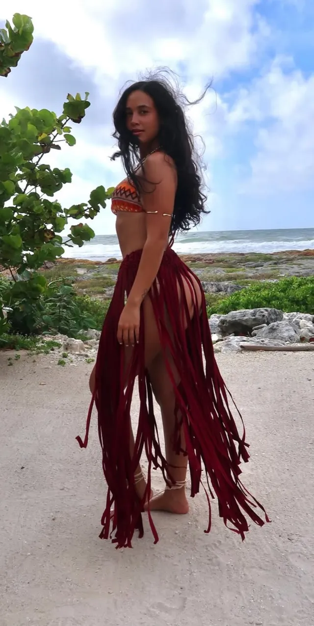 Emily Tosta standing barefoot near the sea.