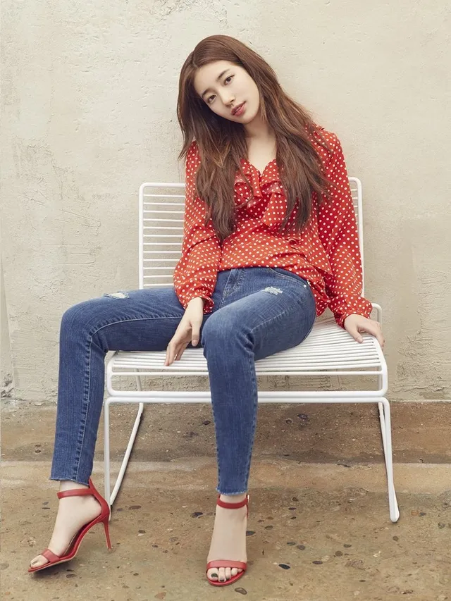 Bae Suzy sitting in a red blouse and red heels.