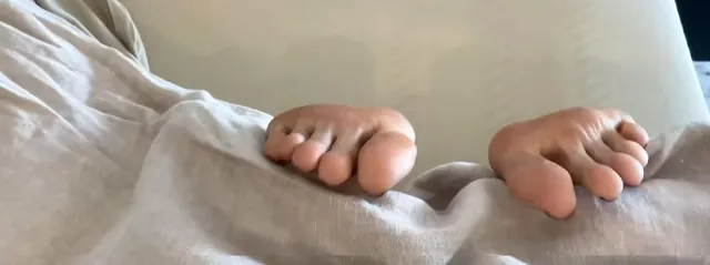 Jessica Alba showing painted bare toes on pale bedding.
