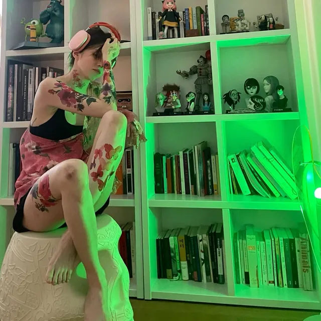 Han So-hee sitting barefoot beside bookshelves.
