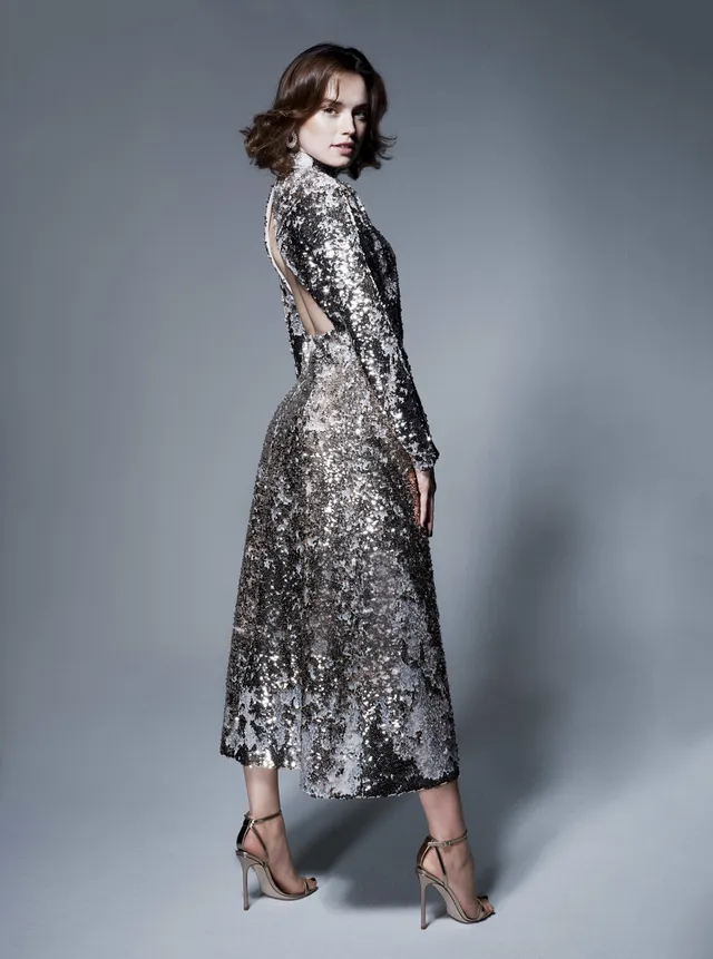 Daisy Ridley posing in a sequinned long dress and sandals.