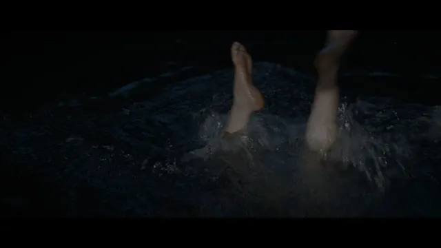 Daisy Ridley swimming at night in a screen scene.