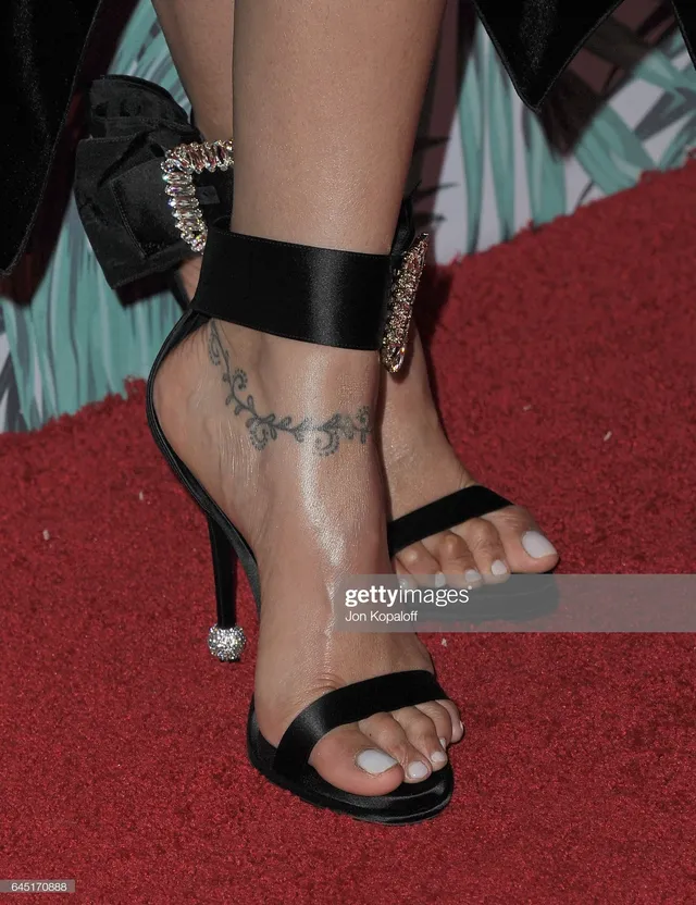 Deepika Padukone showing black ankle-strap heels on a red carpet.