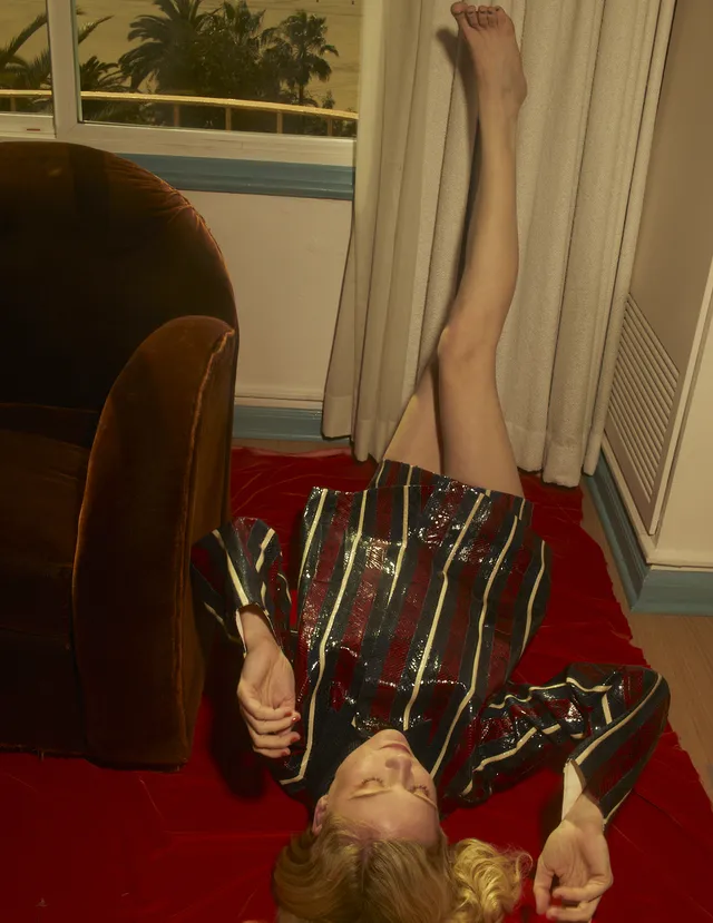 Kirsten Dunst lying on a red sofa with her legs raised.