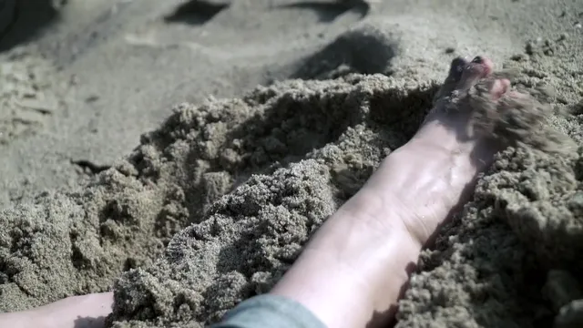 Elisha Cuthbert resting a bare foot in sand.