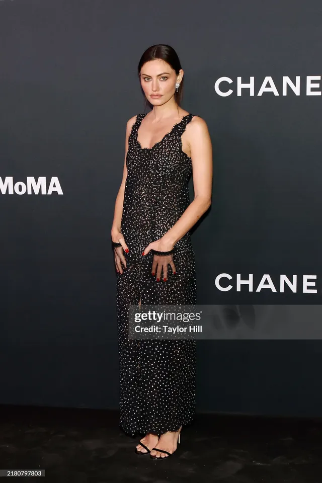 Phoebe Tonkin posing at an event in a dark patterned dress.