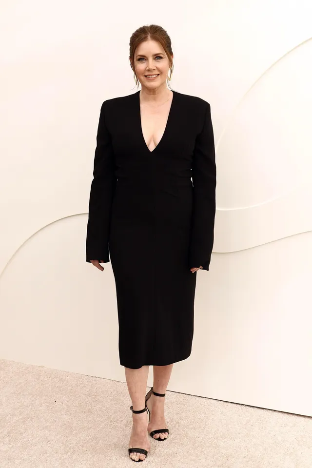 Amy Adams standing at an event in a black dress.