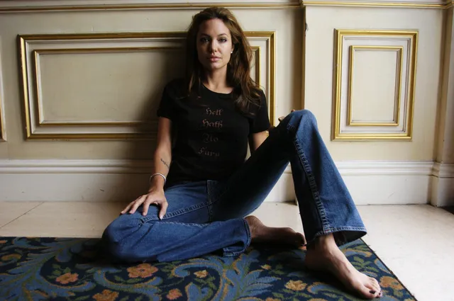 Angelina Jolie seated on the floor in jeans and a dark shirt.