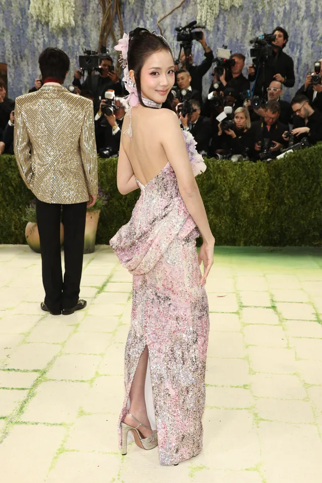 Jisoo wearing pale heels beneath a long patterned pink gown at a fashion event.