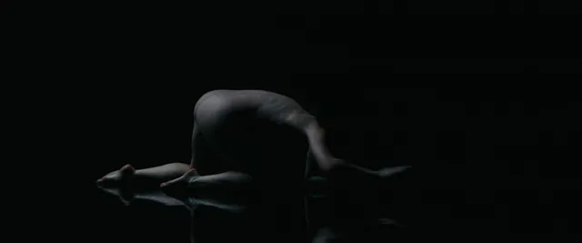 Anne Hathaway posing in a dark stage scene.
