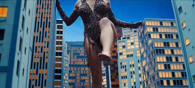 Sydney Sweeney in an action-film still wearing a dark costume above city buildings.