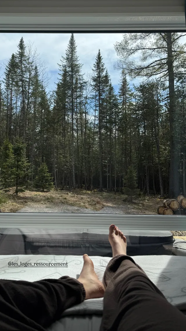 Sophie Nélisse resting bare feet beside a window overlooking woodland.