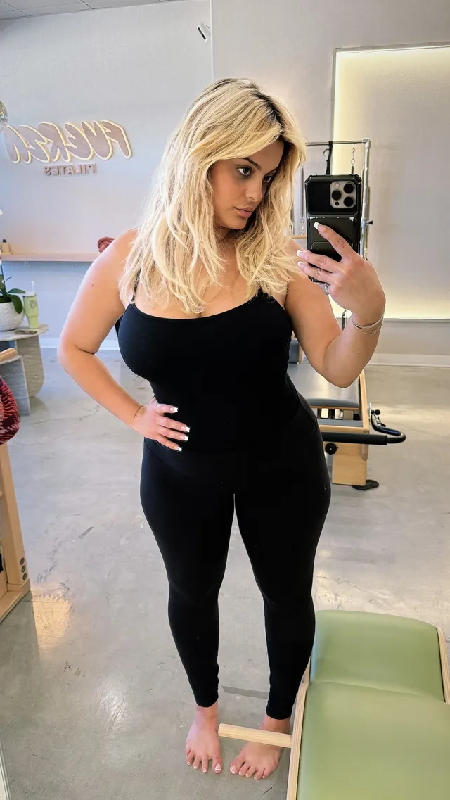 Bebe Rexha taking a mirror photograph while standing barefoot in a black outfit.