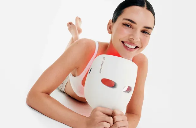 Kendall Jenner lying barefoot in a white studio with a face mask.