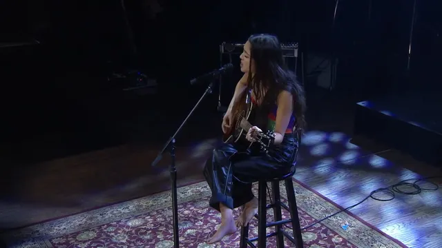 Olivia Rodrigo sitting on a stool during a performance.